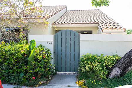 House entrance with a blue-gray gate, white stucco wall, and clay-tile roof.