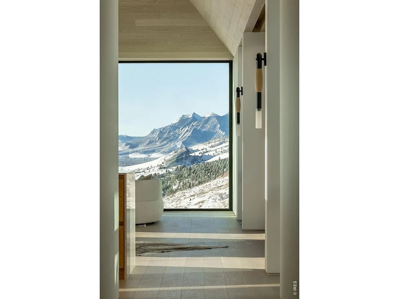 Modern hallway with a floor-to-ceiling window framing a snow-covered mountain view.