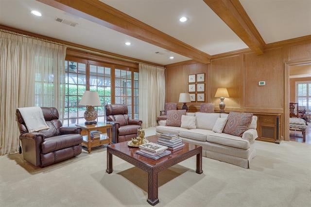 Living room with exposed wood beams, leather armchairs, and a sofa beside a large curtained window.