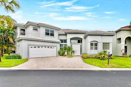 White two-story home with a double garage, broad driveway, and landscaped lawn.