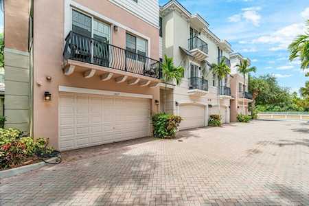 Attached townhomes with balconies and garage doors along a broad brick-paved driveway.