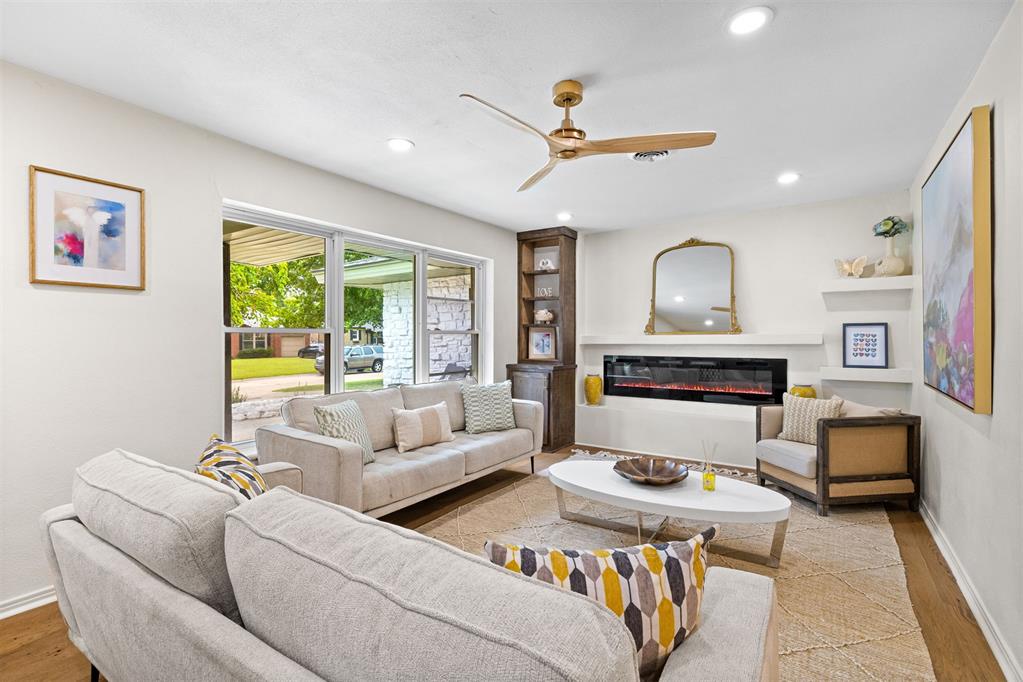 Furnished living room with a modern linear fireplace, large windows, and two sofas.
