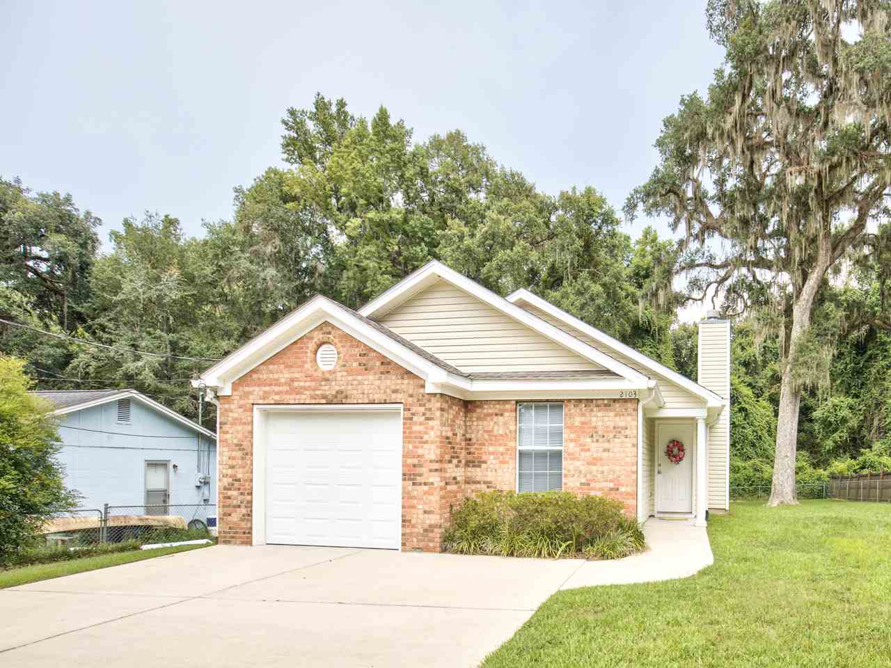 A brick home featuring a garage and a well-maintained driveway.