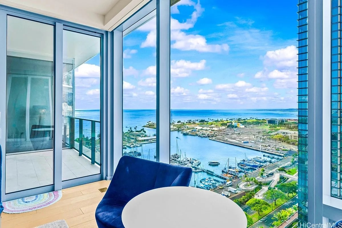 Condo interior with floor-to-ceiling windows overlooking a marina and ocean.