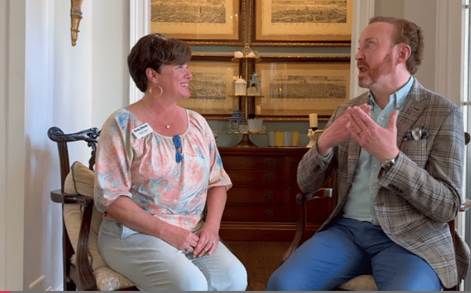 Melanie Wagner and a man discuss Meals on Wheels while seated in a furnished room.