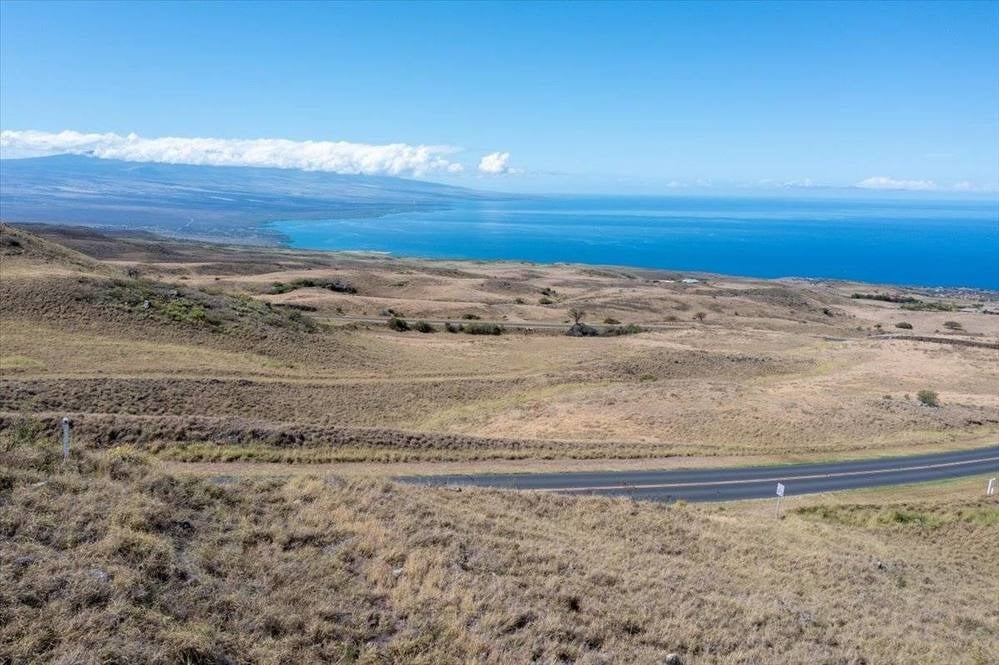 Open grassy land above a road with sweeping views of the ocean and distant coastline.