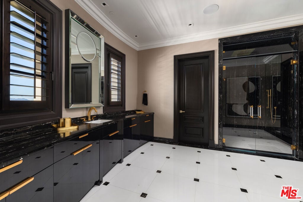 Bathroom with a black marble vanity, gold fixtures, and glass-enclosed shower.