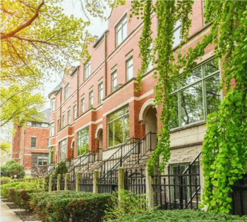 Red-brick building with stone trim, iron railings, and ivy-covered walls.