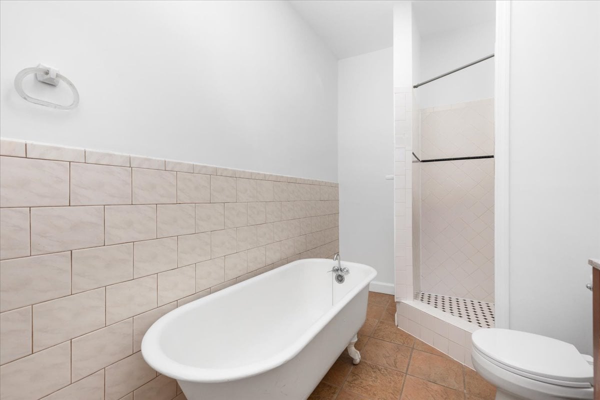 Bathroom with a freestanding white tub, tiled walk-in shower, and toilet.