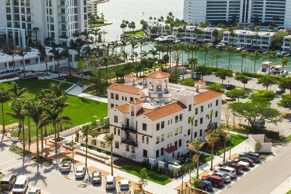 Aerial view of downtown Sarasota condos beside palm-lined waterfront and boats.