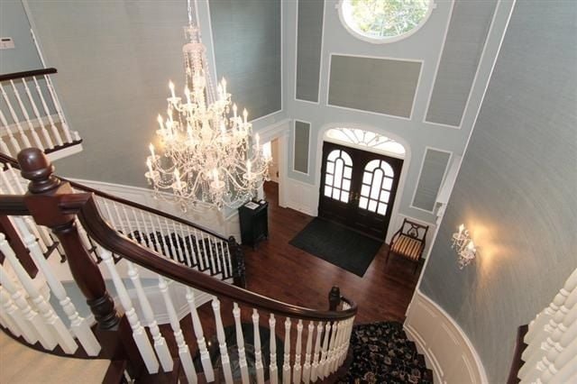 Two-story foyer with a curved staircase, ornate chandelier, and arched double front doors.