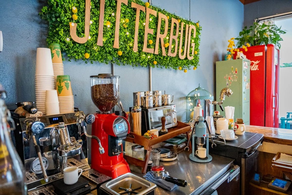 Coffee shop counter with espresso machines, a red grinder, and a large BUTTERBUG sign.