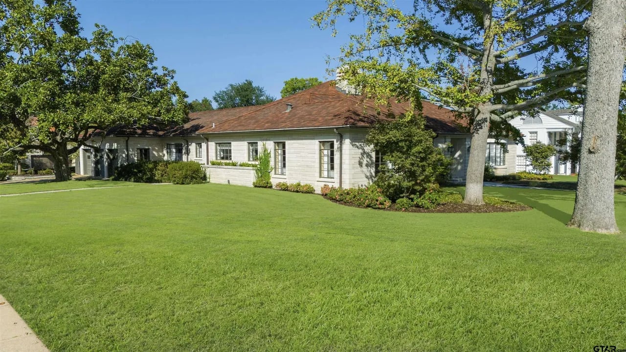 corner lot style photo of house with green grass and white stone exterior red tile roof