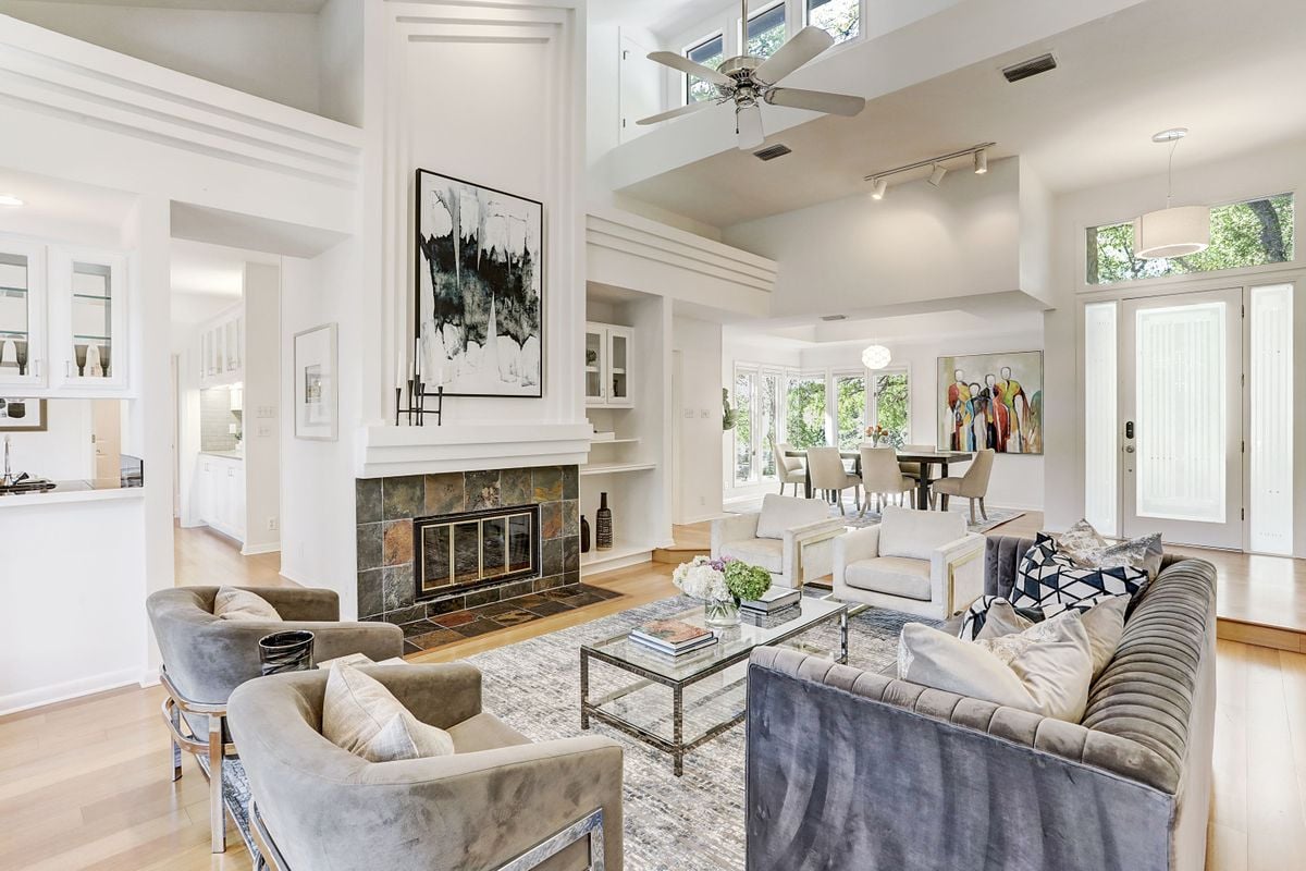 Open great room and dining area at 2131 Barton Hills Drive, Austin, TX 78704, with a vaulted ceiling, clerestory windows, and a stone fireplace beyond. Barton Hills, Austin.