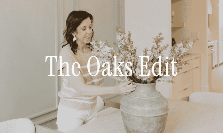 Woman arranging flowers in a vase in a bright interior, overlaid with “The Oaks Edit.”
