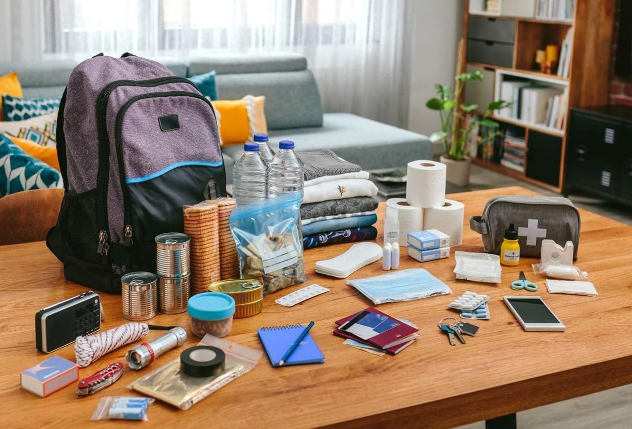Emergency preparedness supplies including bottled water, canned food, flashlights, batteries, first aid kit, and portable chargers