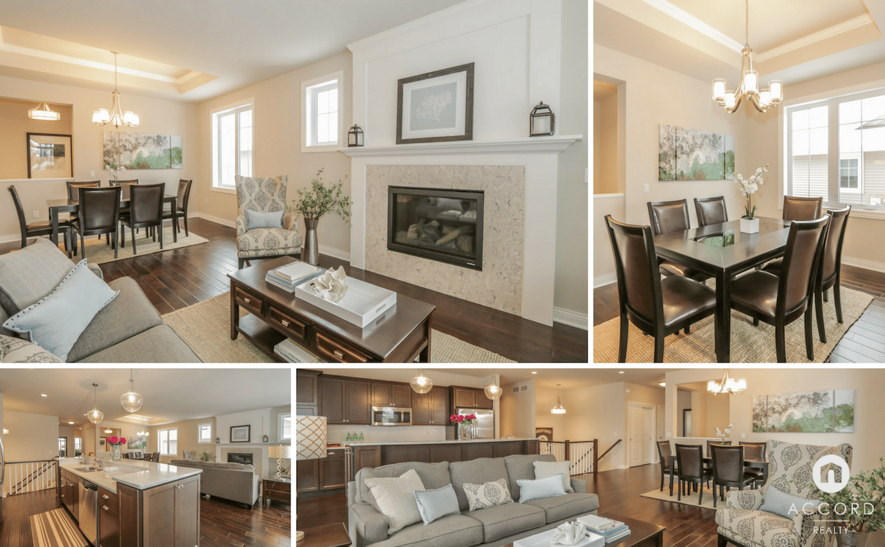 Open-plan living room, dining area, and kitchen with a stone fireplace, dark cabinetry, and wood floors.