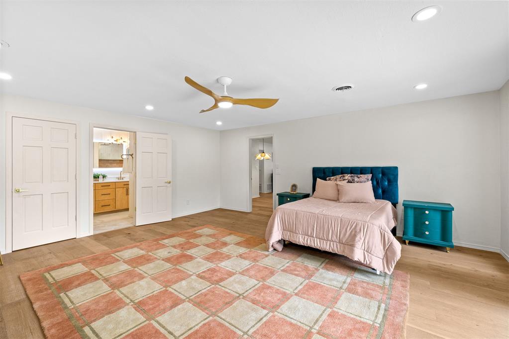 Bedroom with a teal tufted headboard, matching nightstands, and a large patterned rug.