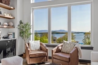 Living room with two armchairs and large windows overlooking a lake.