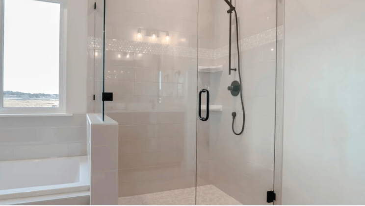 Bathroom with glass walk-in shower, built-in bench, soaking tub, and a window overlooking the water.