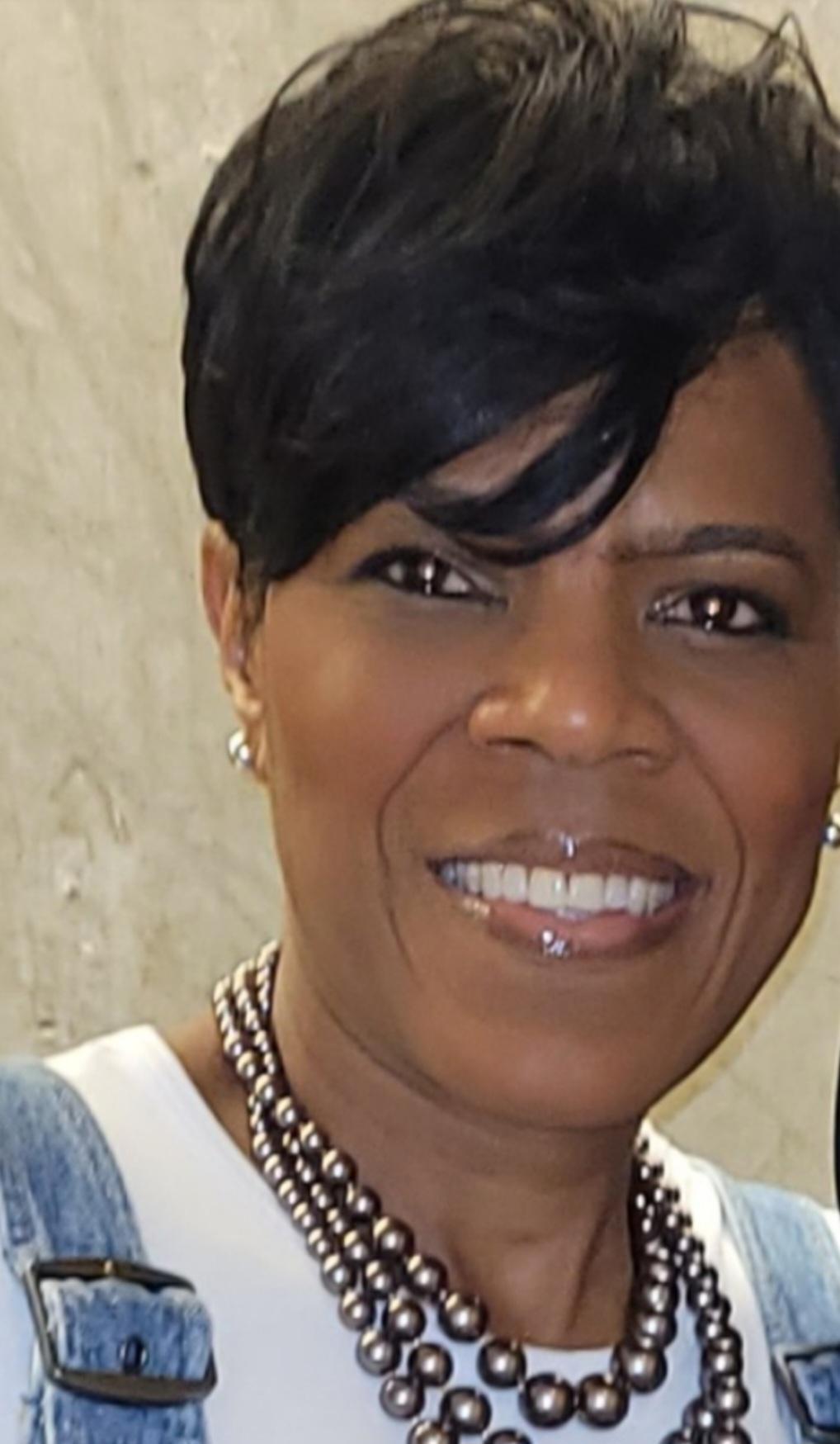 Taryn Dunnaville smiling in a denim jacket and layered beaded necklace.