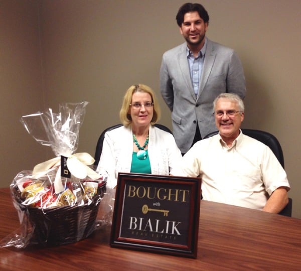 Bruce and Jody with their real estate agent and a Bialik “Bought” sign.