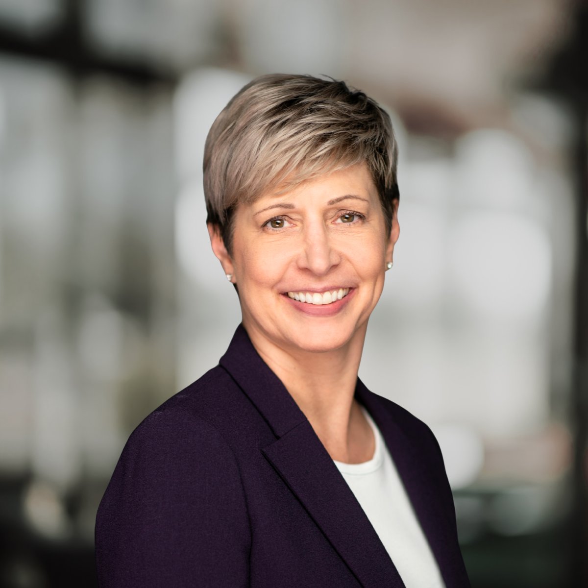 Laura Benner smiling in a dark purple blazer and white top.