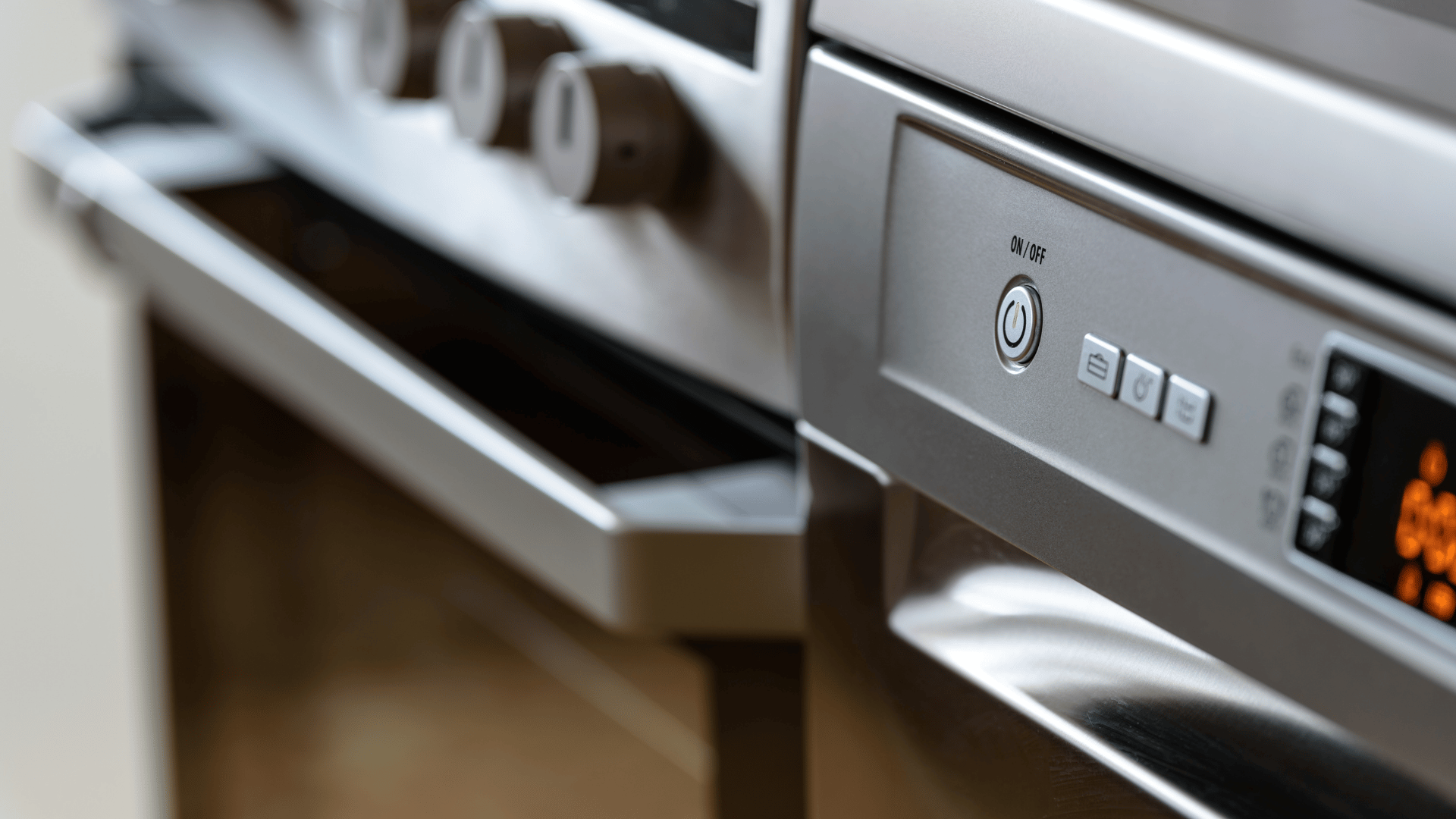 Stainless steel oven beside an open kitchen drawer, with its control panel in focus.