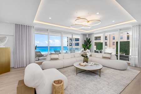 Living room with a curved white sectional and floor-to-ceiling windows overlooking the ocean.