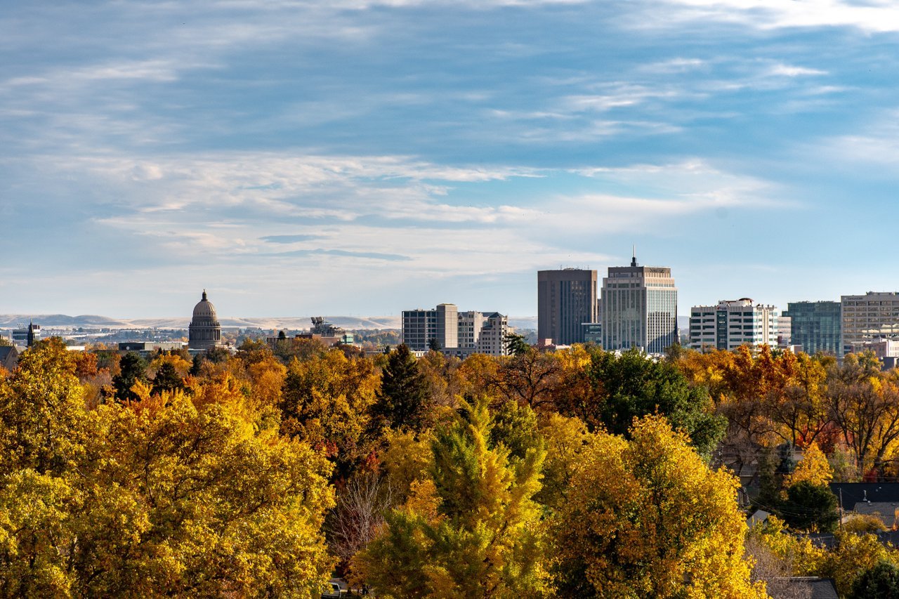 Downtown Boise skyline and Idaho State Capitol above autumn-colored trees.