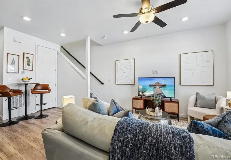 Bright, open-concept living room at 2092 S Upham Way, Denver, CO 80227, featuring a modern sofa, TV console, and ceiling fan.