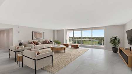 Modern living room with floor-to-ceiling windows overlooking greenery and a balcony.
