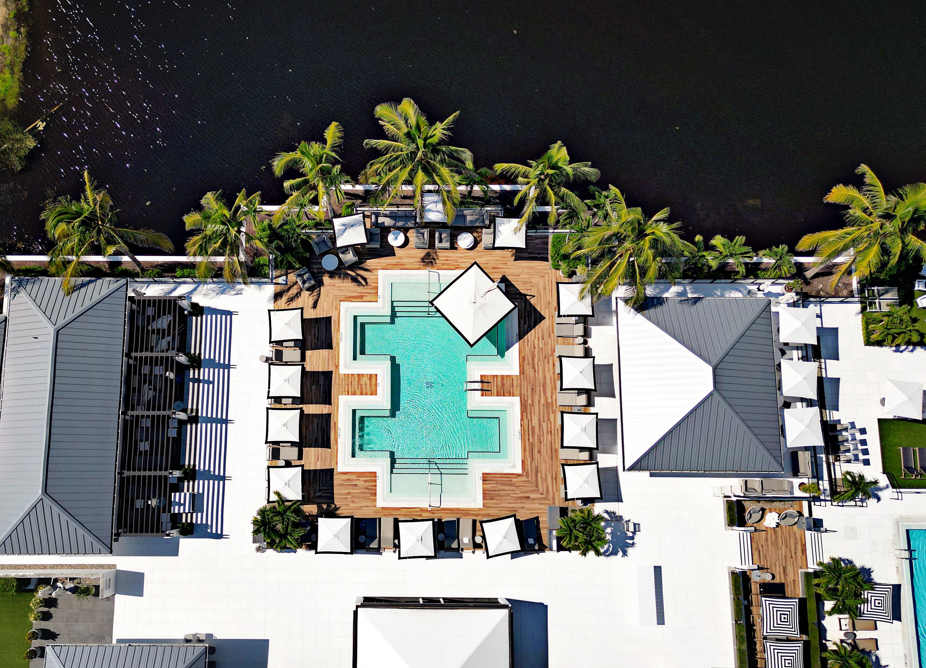 Aerial view of a pool deck with cabanas and palms at Kalea Bay