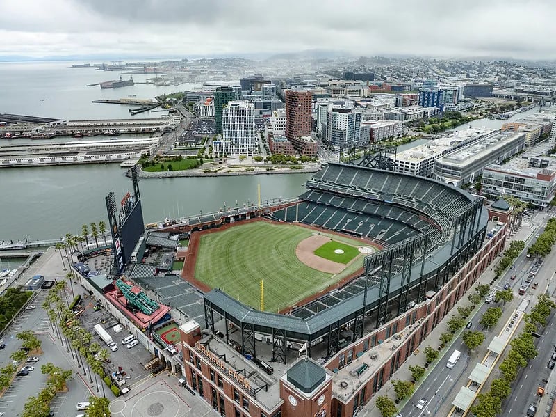 Aerial view of Oracle Park stadium and the Mission Bay neighborhood in San Francisco, showing the ballpark's proximity to the waterfront and urban residential high-rises.