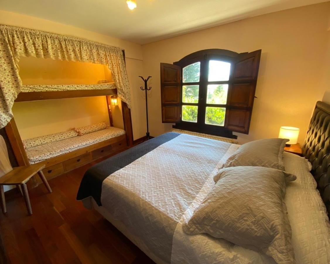 Bedroom with a large quilted bed, curtained built-in bunk, and open wooden shutters.