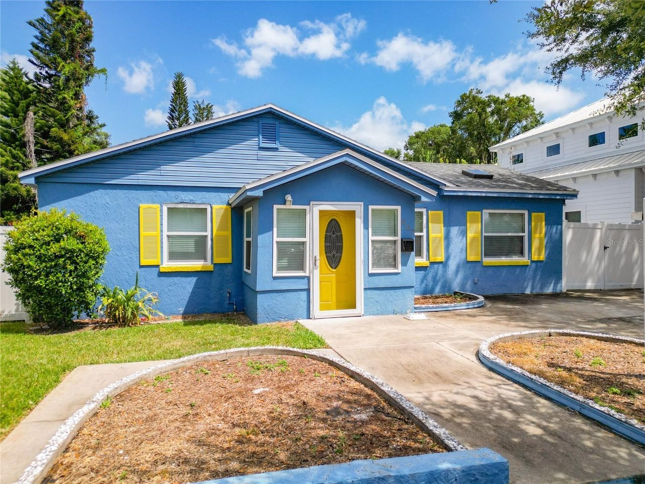Blue single-story house with a bright yellow front door and matching shutters.