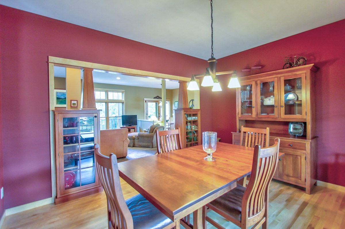 Dining room with red walls, a large wooden table, matching chairs, and glass-front cabinets.