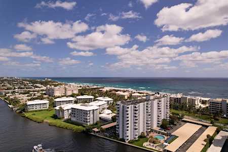 Coastal condominiums beside an inlet, with the ocean and a swimming pool beyond.