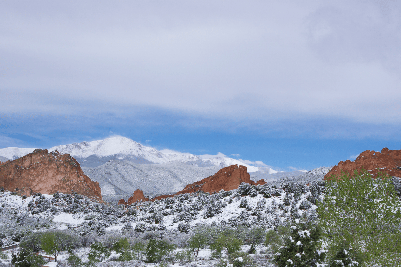 Snow-dusted red rock formations with snow-capped mountains in the distance.