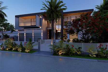 Modern two-story home with large windows and tropical landscaping at dusk.