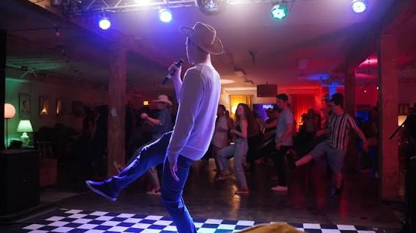 Dancers on checkered floor at colorful nightclub line dancing event