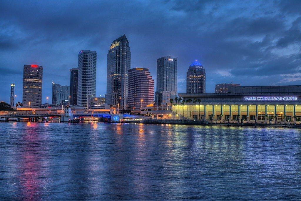 Fog drifting across the Tampa Bay waterfront at blue hour with dramatic clouds and city lights.