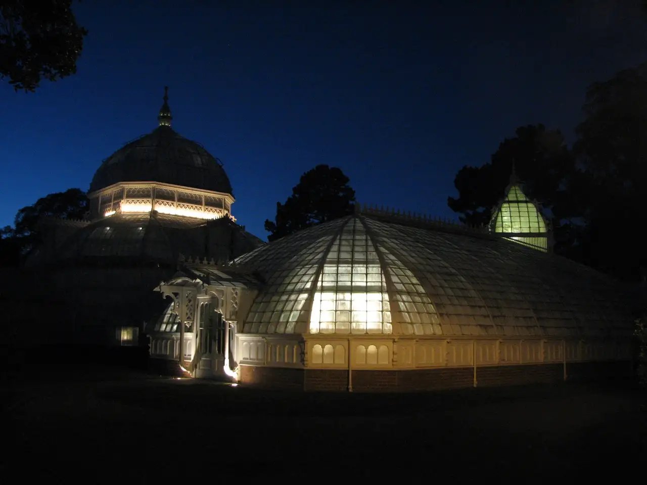 Evening view of the conservatory with its glass walls glowing softly from interior lighting