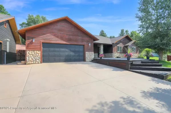 House with a double garage, stone accents, and a raised patio with flower planters.