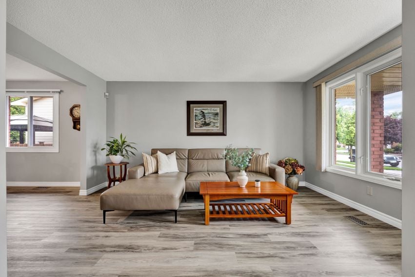 Living room with a beige sectional, wooden coffee table, and large windows.