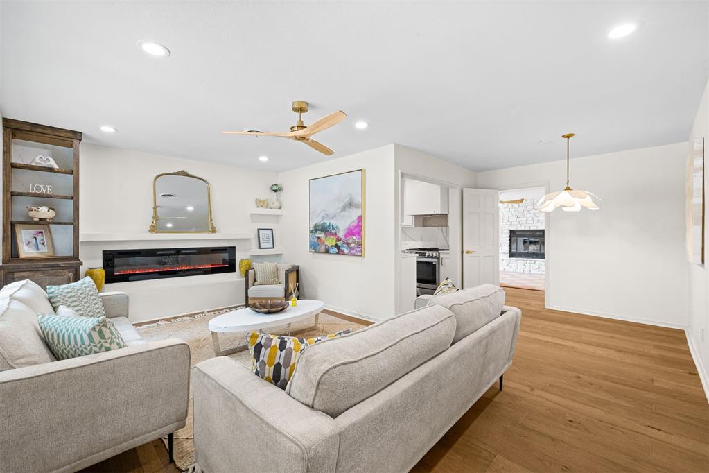 Staged living room with gray sofas, a built-in electric fireplace, and warm wood floors.
