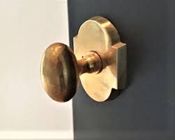 Brass doorknob and lock plate on a two-tone door.