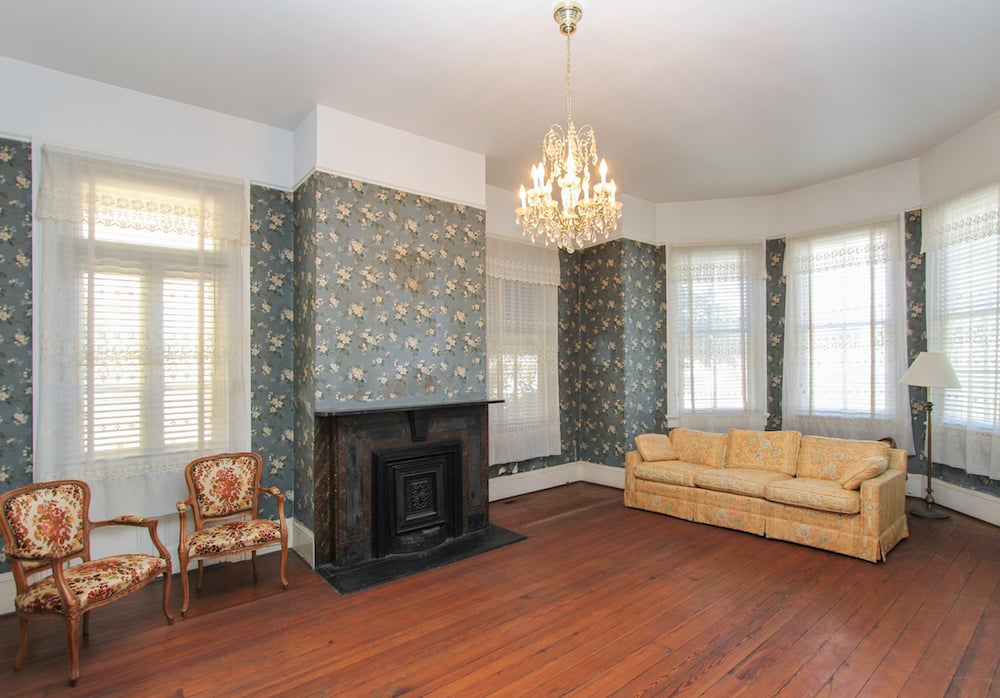 Living room with a black fireplace, floral wallpaper, chandelier, and tall windows.