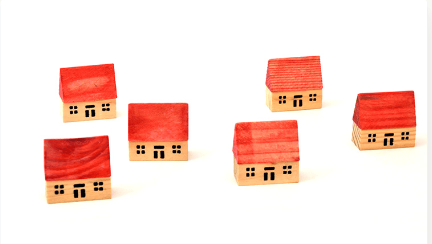 Five wooden model houses with bright red roofs arranged separately.