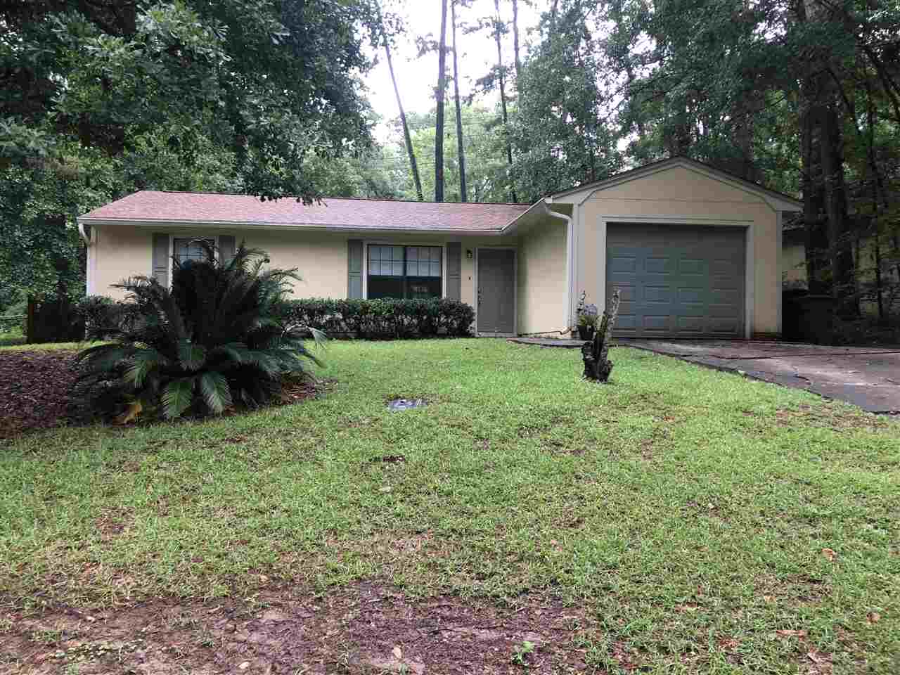 A serene home nestled in the woods, featuring a garage and a spacious yard surrounded by trees.